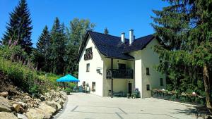 een wit huis met een blauwe paraplu ervoor bij Szafirowy Zakątek in Karpacz