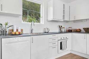 a white kitchen with white cabinets and a window at Hällestrand Village in Strömstad