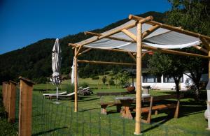 eine hölzerne Pergola mit einem Picknicktisch und einem Sonnenschirm in der Unterkunft Rooms Malina in Blejska Dobrava