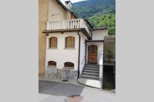een wit huis met een trap en een deur bij Bezauberndes Haus für erholsame Ferien im Puschlav in Campascio
