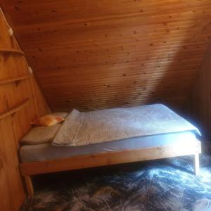 a bed in a wooden cabin with a wooden ceiling at Domek letniskowy Jezioro Białe in Okuninka
