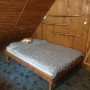 a bed in a wooden room with a roof at Domek letniskowy Jezioro Białe in Okuninka