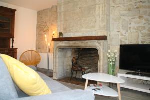 sala de estar con chimenea de piedra y TV en Perhistorique, en Périgueux