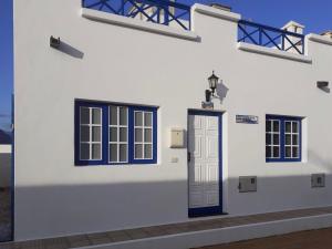 ein weißes Gebäude mit blauen Fenstern und einer Tür in der Unterkunft Casa El Salao in Caleta de Sebo