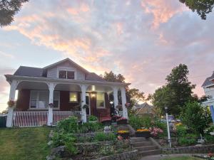 a house with a porch and flowers in the yard at Serene Niagara Inn in Niagara Falls