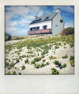 una casa blanca en una playa con plantas en la arena en 180 degrés iodés, en Tréffiagat