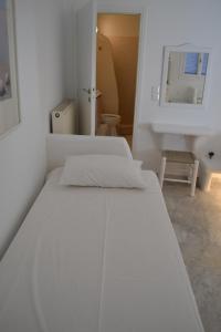 białe łóżko w białym pokoju z lustrem w obiekcie Studio Ioanna Tinos w mieście Kionia