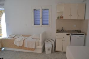 a white bedroom with a bed and a sink at Studio Ioanna Tinos in Kionia
