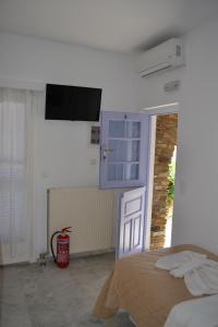 een slaapkamer met een bed en een tv aan de muur bij Studio Ioanna Tinos in Kionia