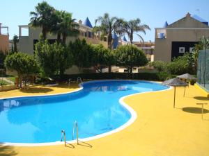 a large blue swimming pool with trees and buildings at Islantur Ipanema in Islantilla