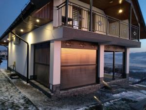 een huis met een balkon en een grote garage bij DOMEK W GÓRACH I NAD JEZIOREM CZORSZTYŃSKIM in Szlembark