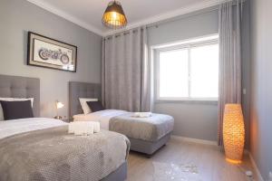 a bedroom with two beds and a window at Golden Beach Apartment in Cascais