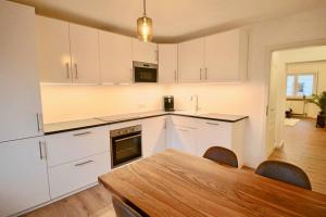 une cuisine avec des placards blancs et une table en bois dans l'établissement Fantastische Moderne und Zentrale Wohnung mit Balkon, à Mannheim