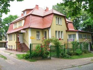 mały żółty dom z czerwonym dachem w obiekcie Hotel Pod Platanami w mieście Trzebnica