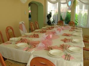 una mesa larga con platos blancos y arcos rosados en Hotel Pod Platanami, en Trzebnica