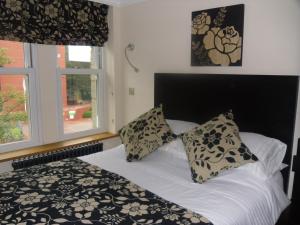 1 cama con almohadas blancas y negras y ventana en The Arc - Boutique B&B, en Harrogate