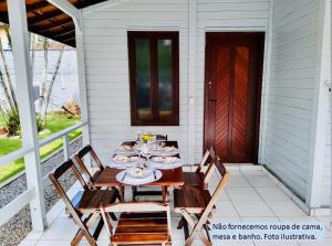 a table and chairs on the porch of a house at Morada do Sol Cambury in Camburi