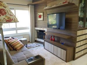 uma sala de estar com um sofá e uma televisão de ecrã plano em Apartamento Gramado em Gramado