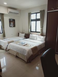 um quarto de hotel com duas camas e uma janela em Frank B&B em Jincheng