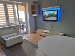 ein Wohnzimmer mit einem Tisch und einem TV an der Wand in der Unterkunft Nad Rustiką in Gdynia