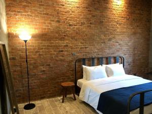 a bedroom with a bed and a brick wall at The Barn Hua Hin in Khao Tao