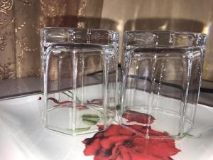 dos jarrones de cristal sentados en un plato con flores rojas en Guest House Ostrov Sokrovishch, en Loo