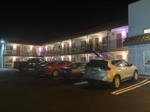 una fila de autos estacionados en un estacionamiento frente a un edificio en PASADENA LODGE, en Pasadena