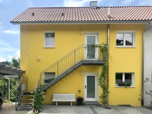 a yellow house with a staircase and a bench at Ferienwohnung Sterntaucher in Überlingen