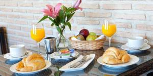 una mesa con cruasanes y una cesta de fruta y zumo de naranja. en Hotel Medina de Toledo, en Toledo