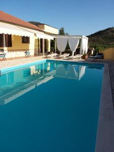 ein blauer Pool mit Stühlen und ein Haus in der Unterkunft B&B Il melograno in Capoterra