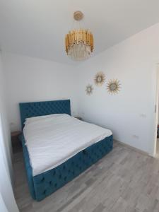 a bedroom with a blue bed with a chandelier at Apartament Lux Eika in Mamaia Sat/Năvodari