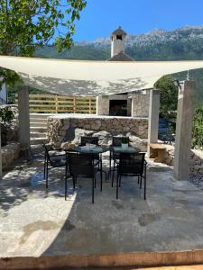 a patio with a table and chairs and a stone fireplace at Mate in Zagvozd