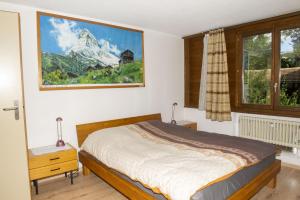 a bedroom with a bed and a picture of a mountain at Lauterbrunnen Staubbach Beautiful Waterfall Apartment in Lauterbrunnen