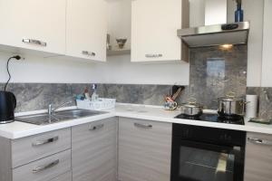 Una cocina con gabinetes blancos y un horno de estufa. en Residence Villa Fiore Portorož, en Portorož 60 fotos más