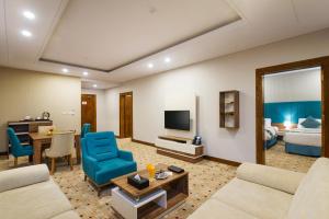 a living room with a couch and a television and a bed at Le Park Concord Hotel - Turaif in Ţurayf