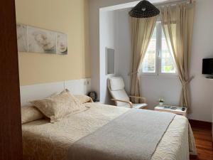1 dormitorio con 1 cama, 1 silla y 1 ventana en SCQ homes, en Santiago de Compostela