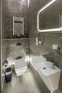 ein Badezimmer mit einem weißen Waschbecken und einem WC in der Unterkunft Studio Doroshenko in Lwiw