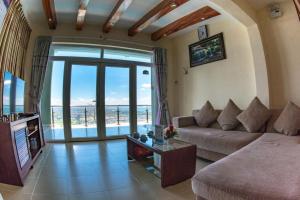 a living room with a couch and a view of the ocean at Ho May Resort in Vung Tau