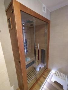 a glass shower door in a room with a bench at Sosnowa Chata - dom z prywatną sauną in Szklarska Poręba