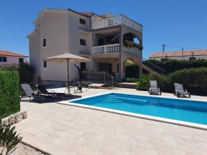 a villa with a swimming pool in front of a house at Apartman Lili in Rogoznica