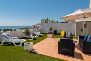 a patio with chairs and an umbrella and grass at MAKENZY Seaview PENTHOUSE in Larnaka