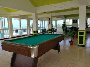 una mesa de billar en una habitación grande con ventanas en Orient Guesthouse Auberge, en Mahébourg