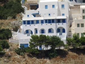 une maison blanche sur une colline avec des arbres dans l'établissement Panselinos, à Anáfi