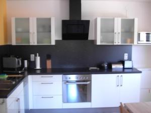 uma cozinha com armários brancos e um forno com placa de fogão em Haus Maximilian em Rammelsbach