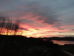 einen Sonnenuntergang über einem Wasserkörper mit einem Himmel in der Unterkunft Le garage de Sophie in Aiguebelette-le-Lac