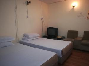 Cette chambre comprend deux lits, une télévision et un canapé. dans l'établissement MIRAMAR HOTEL, à Sibu