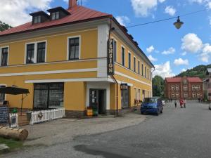a yellow building with a car parked in front of it at Penzion U Hlaváčů in Horní Maršov