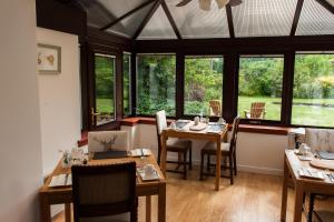 a dining room with tables and chairs and windows at Kilmore Farmhouse in Drumnadrochit