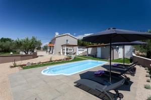 a swimming pool with two chairs and an umbrella at Villa Frana in Krk