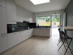 a kitchen with white cabinets and a large window at Kitrino in Geel